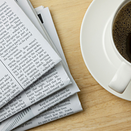 picture of a stack of newspapers and a cup of coffee